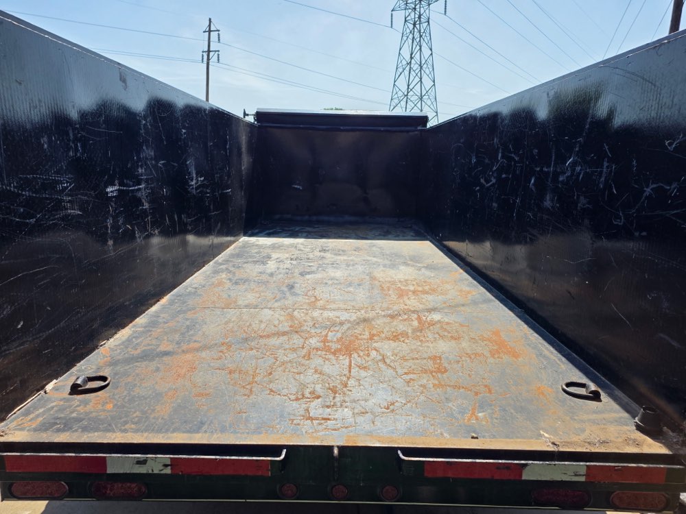 Interior view of the dump trailer bed, raised, showing the heavy steel floor and side walls